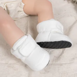 Detailed view of non-slip rubber sole and velcro strap on white soft infant shoes
