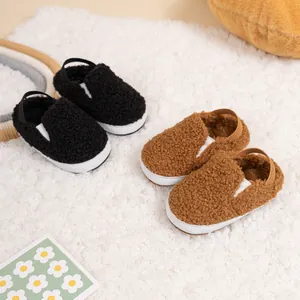 Plush baby walking shoes in black and brown styles on a cozy white fleece carpet