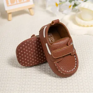 Close-up of brown leather baby shoes with lychee texture and white stitching details