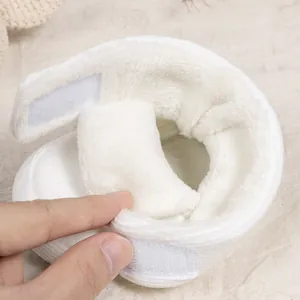 Detail of warm white baby bootie showing soft plush lining and velcro strap closure