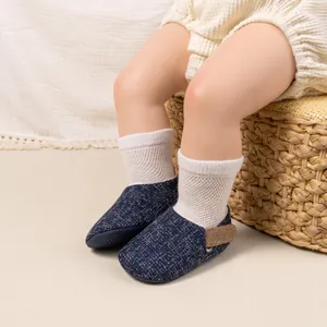 Close-up of navy blue breathable baby walking shoes with white mesh socks in a cozy setting