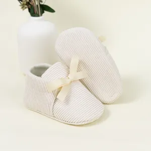 Close-up of beige corduroy baby shoes with satin bows and soft anti-slip soles