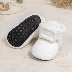Detail of white corduroy baby boots showing non-slip sole and magic tape closure