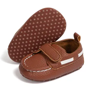 Detail showing the brown baby moccasins with anti-slip dotted sole and velcro strap