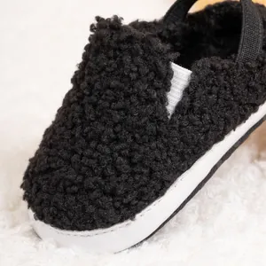 Close-up of soft black fleece baby shoes featuring cozy plush texture and elastic heel strap