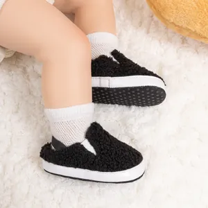 Detail view of baby walking slippers featuring black faux shearling and soft white soles