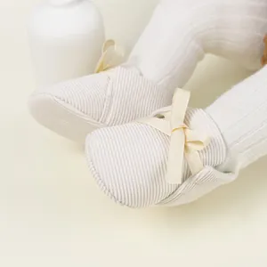 Detailed view of beige ribbed baby loafers with a decorative bow and soft sole