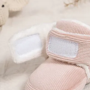 Close-up of pink corduroy baby boots with warm faux fur lining and velcro strap closure