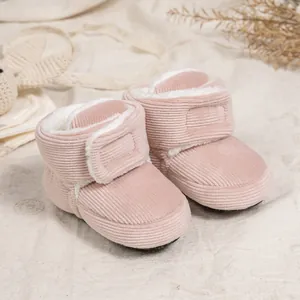 Pink corduroy baby boots with warm fleece lining and velcro closure on linen background