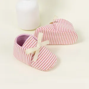 Close-up of pink striped baby shoes featuring a soft cream-colored ribbon bow detail