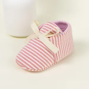 Close-up of pink striped baby shoe with a delicate ribbon bow and breathable cotton texture