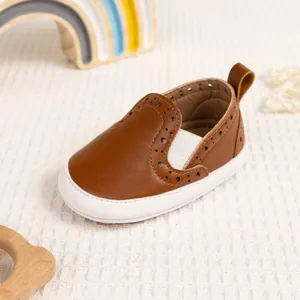 Dettaglio di mocassini per bambini in pelle marrone con decorazioni e suole in gomma