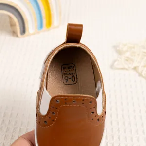 Dettaglio scarpe neonato in pelle marrone con fori brogue ed etichetta taglia 0-6 mesi