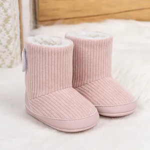 Rosa Baby-Stiefel aus Cord mit warmem Lammwollfutter auf einem dekorativen Holzgrund