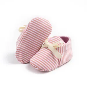 Detail of pink and white striped soft-sole baby shoes with a cream ribbon bow