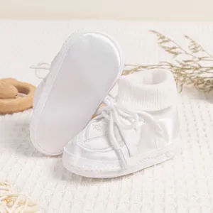 Detail of white satin baby baptism shoes with diamond embroidery and ribbed ankle cuffs