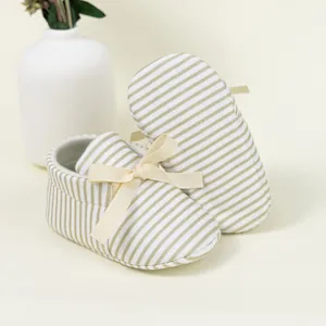 Detail of striped baby shoes with non-slip soft soles and decorative ribbon bow