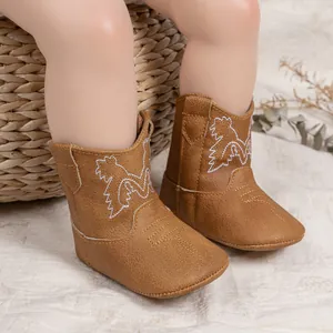 Détail de bottes de cowboy marron pour bébé avec broderie blanche sur cuir PU souple