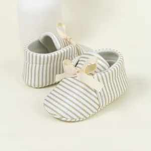 Detail of baby soft sole striped shoes with a cute beige satin bow decoration