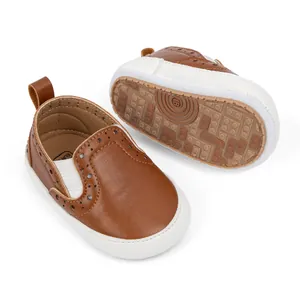 Dettaglio di scarpe da neonato slip-on con motivi brogue e suole antiscivolo