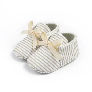 Close-up of baby loafers featuring striped cotton fabric and a decorative satin bow detail