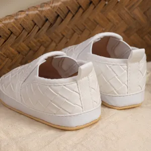 Close-up of white woven slip-on baby shoes with soft non-slip soles for infants