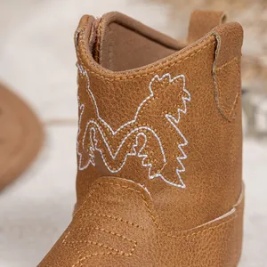 Détail de bottes de cowboy pour bébé en cuir grainé marron avec broderie blanche chic