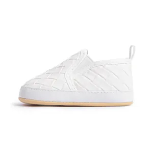 Detail view of woven white baby walking shoes with soft brown soles and easy pull tabs