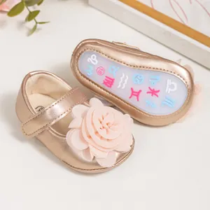 Détail de chaussures bébé dorées avec fleurs 3D en résille et semelles à motifs zodiaque