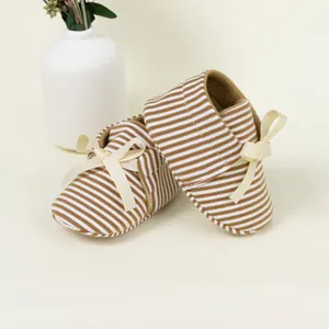 Close-up of baby loafers with brown and white stripes and a decorative ribbon bow