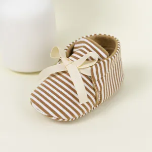 Detailed close-up of brown striped baby shoes with soft soles and decorative bow