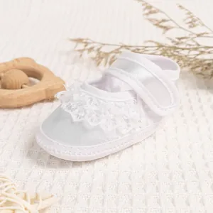 Detailed macro of white satin baby walker shoes with delicate lace trim and velcro strap