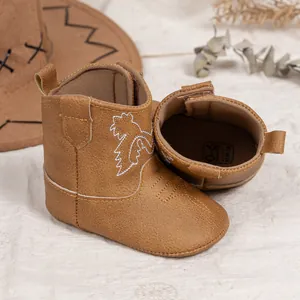 Détail de bottes cowboy bébé montrant l'étiquette de taille 0-6 mois et broderie de feuilles