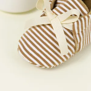 Close-up of baby shoes with brown stripes and decorative cream-colored ribbon bow