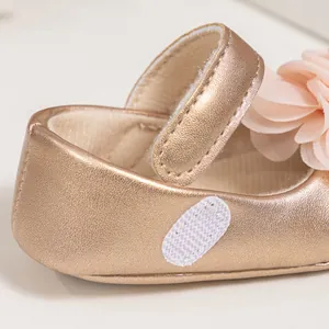 Détail de chaussure Mary Jane pour bébé dorée avec fleur en tissu et velcro ajustable