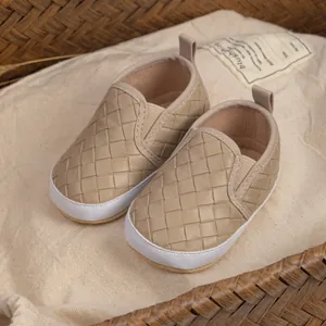Detail of woven beige leather baby shoes with soft white soles in a woven basket