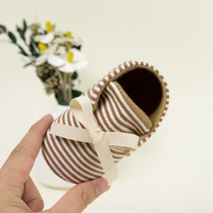 Detail of baby soft-sole shoes with brown striped pattern and cream ribbon bow detail