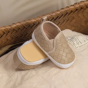 Detail of woven khaki baby shoes with soft soles placed on a natural cotton fabric