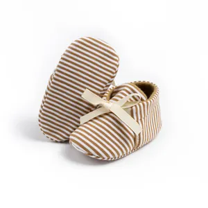 Close-up of brown striped baby shoes featuring a decorative cream ribbon bow