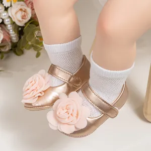 Gros plan de chaussures bébé dorées avec fleurs en mousseline rose et velcro pratique