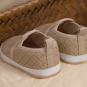 Macro view of baby slip-on shoes showing woven leather texture and soft anti-slip soles