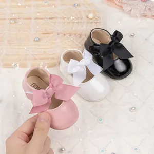Close-up of pink baby Mary Jane shoe with large ribbon bow and velcro strap detail