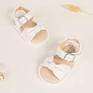Close-up of cream baby sandals with bow and size label 0-6 months for infants