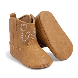 Gros plan de bottes de cowboy pour bébé marron clair avec broderie blanche et semelle souple
