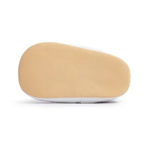 Detailed macro view of non-slip soft sole on white infant walker shoes with neat stitching