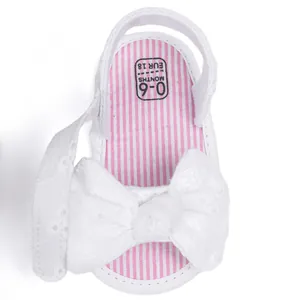 Detail of baby girl sandals with white bow embroidery and pink striped lining