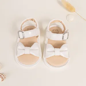 Top view of white baby sandals featuring a large bow decoration and velcro strap