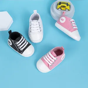 Vue détaillée de dessus des chaussures en toile pour bébé en noir, blanc et rose sur bleu