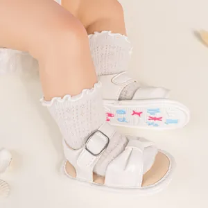 Close-up of white baby sandals with bow detail and non-slip rubber soles for toddlers