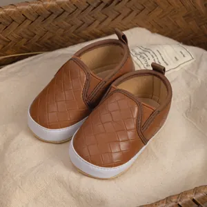 Detail of baby walking shoes with brown woven leather texture and soft white sole